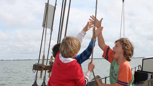 Kinderen trekken samen aan een lijn om het zeil te hijsen