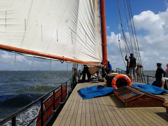 Gasten aan dek onder de zeilen van de Avontuur