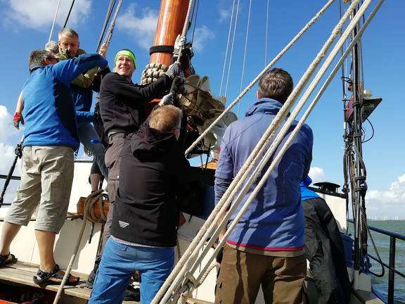 Gasten hijsen samen het zeil van de Avontuur