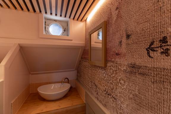 Wastafel onder een patrijspoort in een hut van de Avontuur