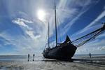 Tjalk Aagtje drooggevallen op het Wad met mensen naast het schip