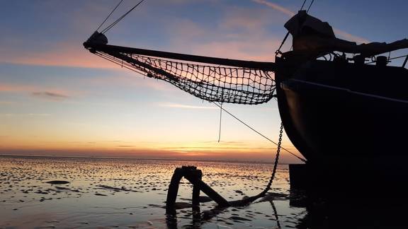 Boeg van tjalk Aagtje bij zonsondergang op het Wad