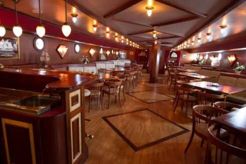 Houten salon met bar en tafels aan boord van de Abel Tasman