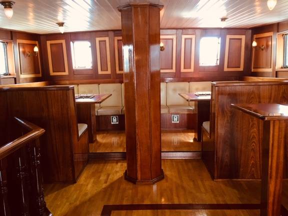 Houten zitbanken en tafels in de salon van de Abel Tasman