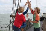 Kinderen helpen samen een zeil hijsen op de Albatros