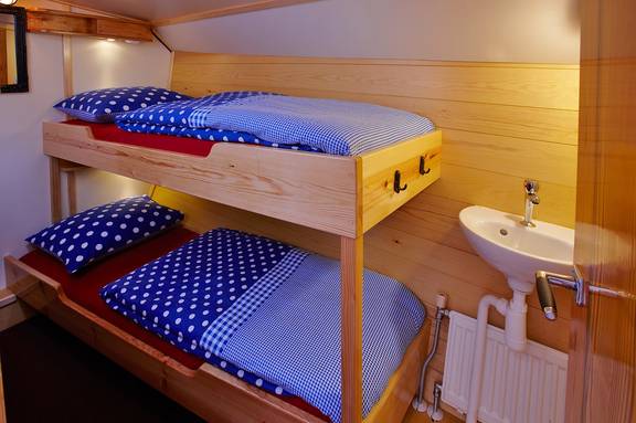 Houten stapelbed en wastafel in een hut van de Albatros