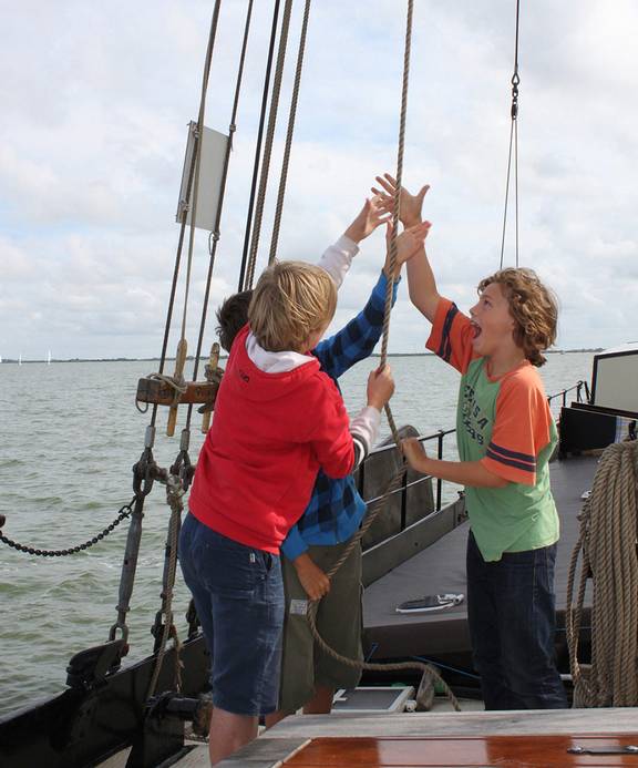Kinderen helpen samen een zeil hijsen op de Albatros