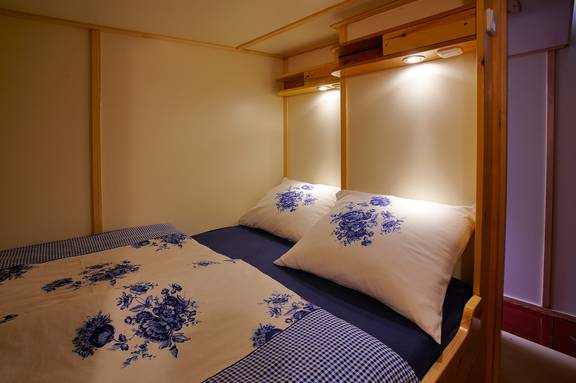 Tweepersoonsbedstee met blauw-wit beddengoed op de Albatros