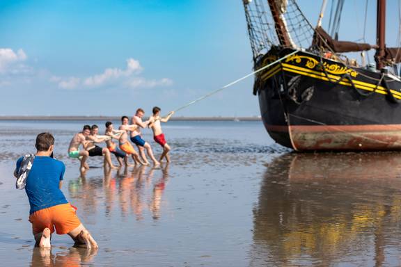 Scholieren poseren naast de Ambiance op het drooggevallen Wad