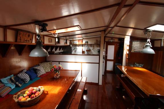 Salon van de Anna Trijntje met houten tafels en blauwe zitbanken