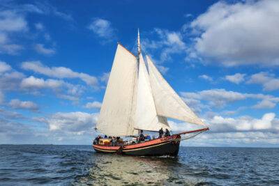 Klipper Anna met witte zeilen onder een blauwe lucht