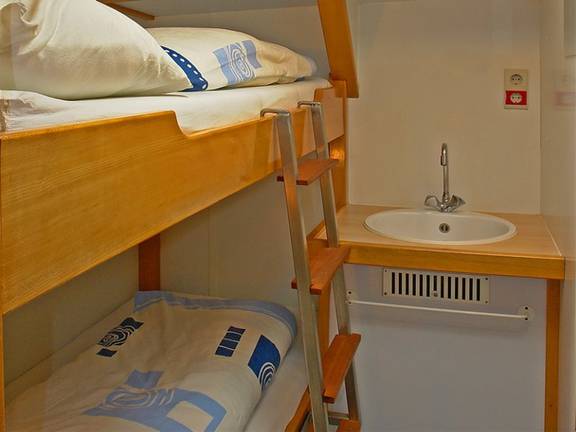 Houten stapelbed en wastafel in een hut van de Avanti