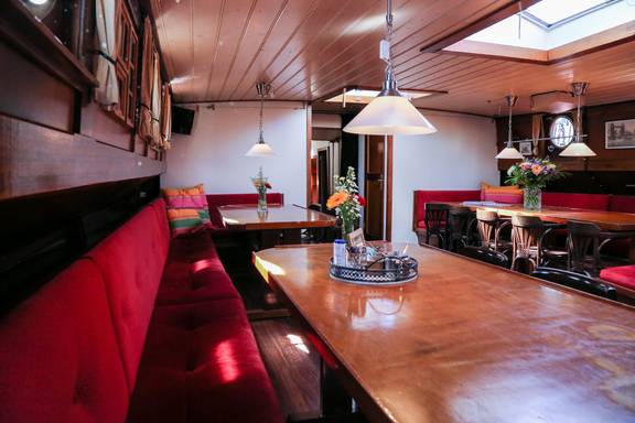 Salon van de Avondrood met houten eettafels en rode zitbanken