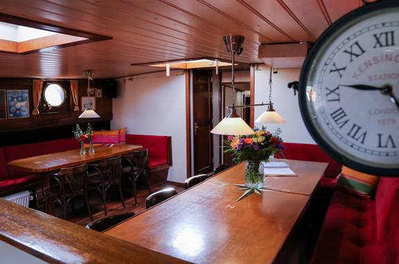 Eettafels en wandklok in de salon van de Avondrood