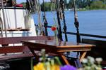 Houten tafel aan dek van de Avondrood met uitzicht op het water
