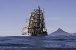 Bark Europa zeilt langs een bergachtige kust