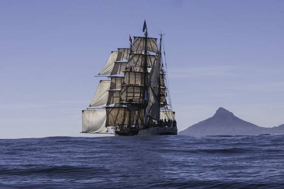 Bark Europa zeilt langs een bergachtige kust