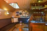 Houten bar en zithoek met scheepsdecoratie op de Boekanier
