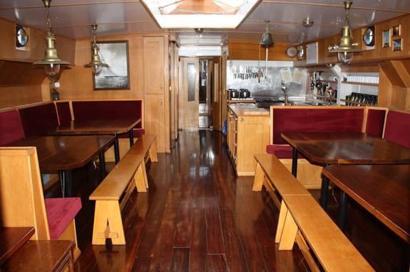 Salon van de Broedertrouw met houten eettafels en rode zitbanken
