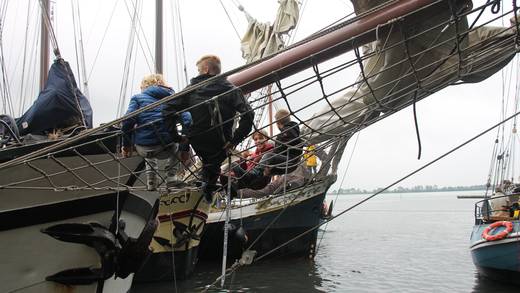 Gasten stappen via de loopplank aan boord van een zeilschip