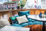 Zithoek met turquoise kussens op het achterdek van de Dame van Amstel