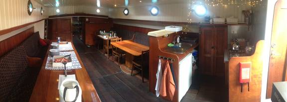 Salon van de Dankbaarheid met houten tafels en zitbanken