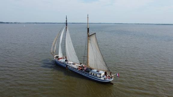 De Hester onder zeil op open water, vanuit de lucht gezien