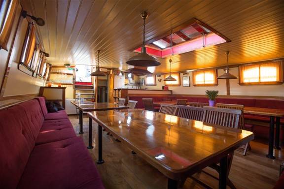 Salon van de Eenhoorn met houten tafels en rode zitbanken