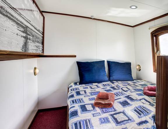 Tweepersoonsbed met blauwe kussens in een hut van de Elizabeth