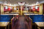 Salon van de Elizabeth met blauwe zitbanken en houten tafels
