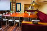 Salon van de Gouwzee met houten eettafels en rode zitbanken