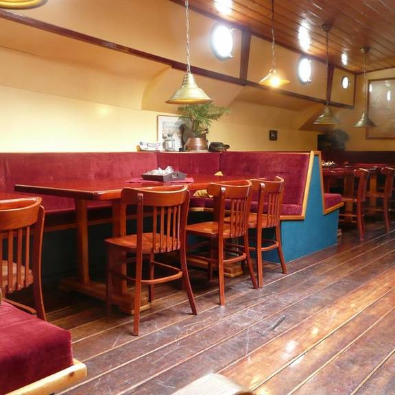 Salon van de Gouwzee met houten eettafels en rode zitbanken