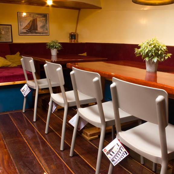 Salon van de Gouwzee met houten eettafels en rode zitbanken