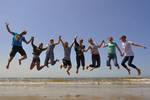 Groep scholieren springt samen omhoog op het strand