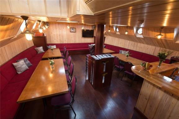 Salon van de Grietje met houten eettafels en rode zitbanken