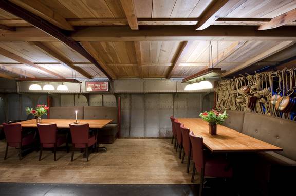 Zitbanken en eettafels onder het houten plafond van de Helena