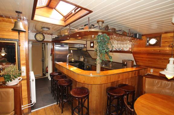 Houten bar met barkrukken naast de kombuis van de Korevaer