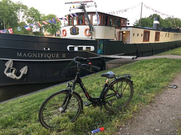Fiets op de oever naast het passagiersschip Magnifique II