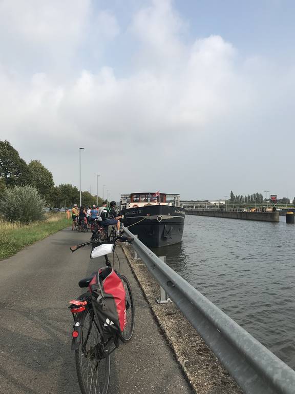Fietsers langs het kanaal bij de aangemeerde Magnifique III