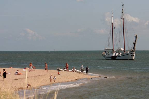 Tweemastklipper Mars ligt bij een zandbank met zwemmers op de Waddenzee