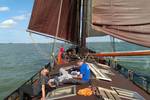 Gasten ontspannen op het dek van de Medusa onder bruine zeilen