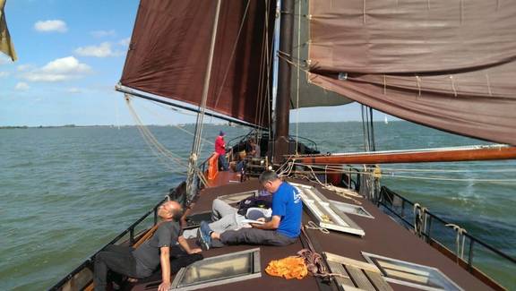 Gasten ontspannen op het dek van de Medusa onder bruine zeilen
