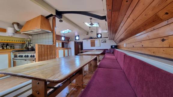 Salon van de Medusa met lange houten tafels en rode zitbanken