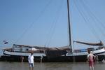 Tjalk Nieuwe Zorg drooggevallen op het Wad met gasten naast het schip