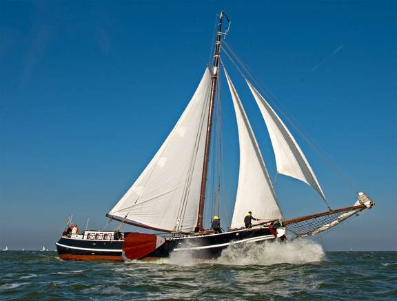 Tjalk Orion met witte zeilen op het water