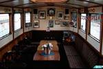 Houten salon met zitbanken en tafels aan boord van de Oude Maze