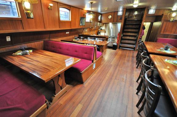 Salon van de Passaat met houten eettafels en rode zitbanken