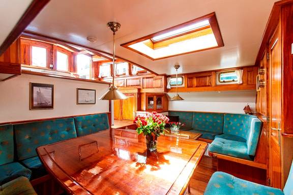 Salon van de Pelikaan met houten eettafel en groene zitbanken