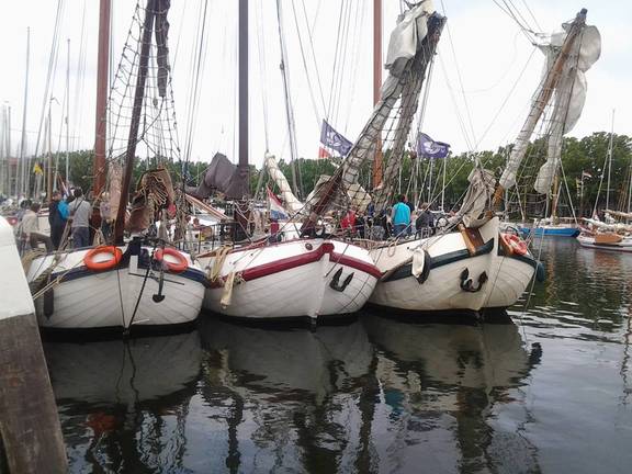 Tjalk Pelikaan afgemeerd tussen andere schepen in de haven