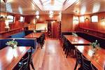 Salon van de Poseidon met houten eettafels en blauwe zitbanken